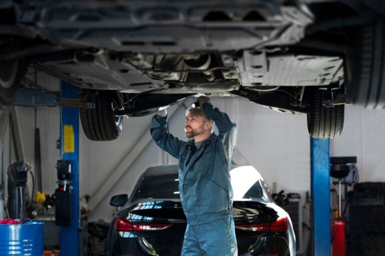 Mechanik kontroluje podvozok auta zdvihnutého na zdviháku